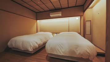 A room with two beds, a ceiling air conditioner, and a wall-mounted light fixture.
