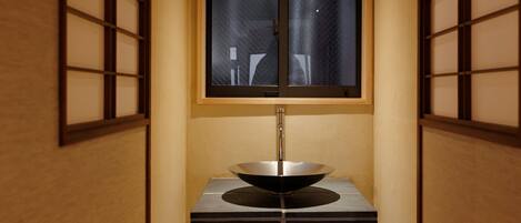 A narrow hallway with a wooden floor, a window with frosted glass, and a sink with a modern design.