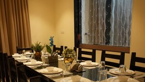 A dining area with a long table set for six, surrounded by chairs. - Cozy Cliff By Marwar Royal – Private Villa with Pool (Barodiya)