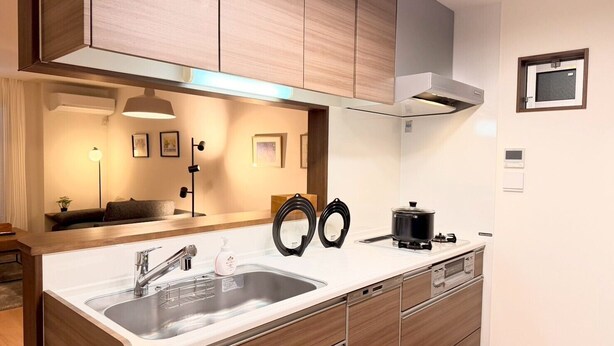 Una cocina moderna con armarios de madera, un lavamanos de acero inoxidable y un horno empotrado.