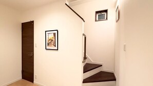 Una escalera de madera oscura con barandilla que lleva a un rellano con un ventanal pequeño.