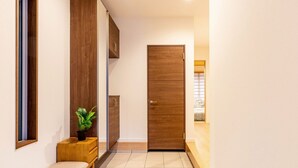 Un pasillo con un banco, una planta en maceta y una puerta de madera.