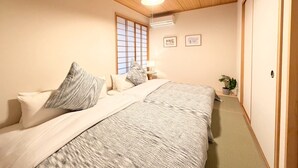 Un dormitorio con techo de madera, una cama con manta estampada, una ventana con vistas y una mesita de noche con lámpara.