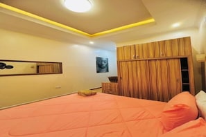 A bedroom with a bed, wooden wardrobe, and a mirror on the wall.