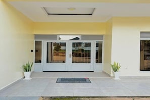 A building entrance with a glass door, potted plants, and a tiled floor. - Spacious 2BR in Lively Neighborhood • Near Airport • Family Ready (Kigali)
