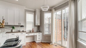 A modern kitchen with white cabinets, a granite countertop, and a dining area with black chairs. - 6 Mi to Buckley Space Force Base: Getaway w/ Patio (Aurora)