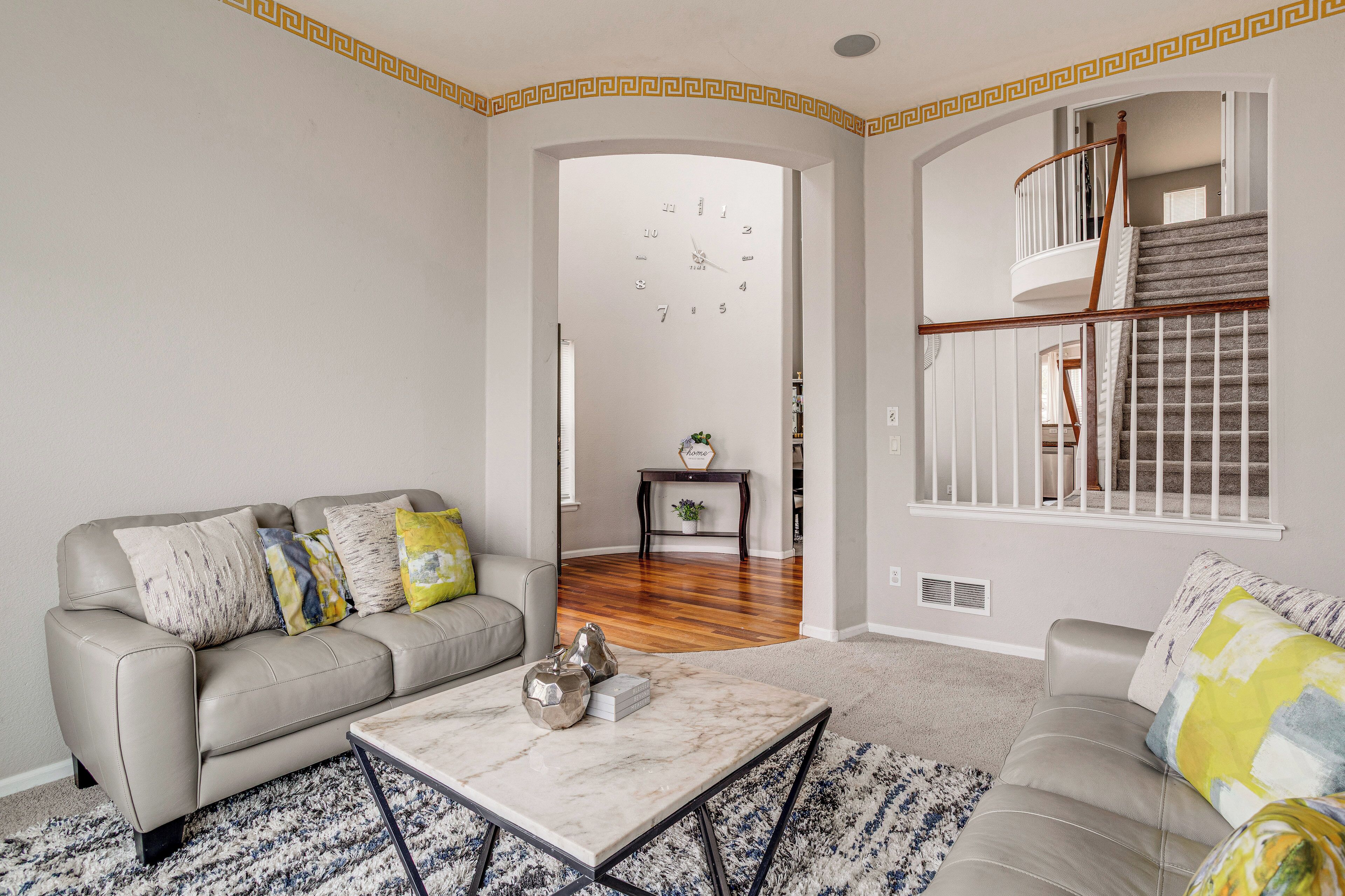 A living room with a sofa, a coffee table, and a staircase.
