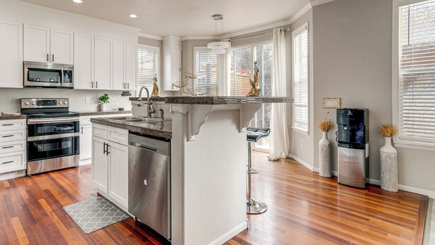A modern kitchen with white cabinets, stainless steel appliances, and a wooden floor. - 6 Mi to Buckley Space Force Base: Getaway w/ Patio (Aurora)