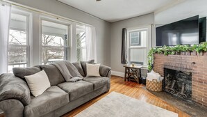 A living room with a gray sofa, a fireplace, and large windows. - 8 Mi to Micron Technology! Walkable Phoenix Gem (Phoenix)
