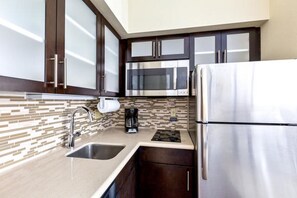 A modern kitchen with stainless steel appliances, dark wooden cabinets, and a tiled backsplash.