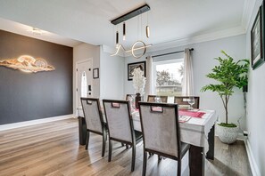 A dining area with a wooden floor, a table set for four, and a hanging light fixture. - Private 1-Acre Hideaway, 2 Mi to Joe Pool Lake! (Grand Prairie)
