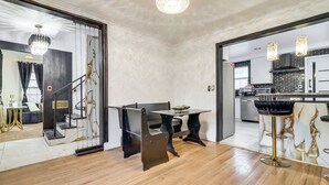 Une cuisine moderne dotée d’un îlot central, d’un coin repas avec une table et des chaises noires, et d’un escalier menant à un autre niveau.