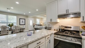 A modern kitchen with white cabinets, a stainless steel stove, and a marble countertop.