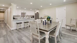 A spacious kitchen with white cabinets, a central island, and a dining area with a wooden table and white chairs.
