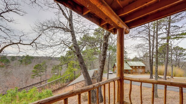 Una terraza de madera con vistas a un área boscosa y una cabaña al fondo.