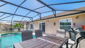 A covered outdoor area with a pool, a table, and chairs. - 5 Mi to Disney: Renovated Group Getaway, Game Room (Kissimmee)