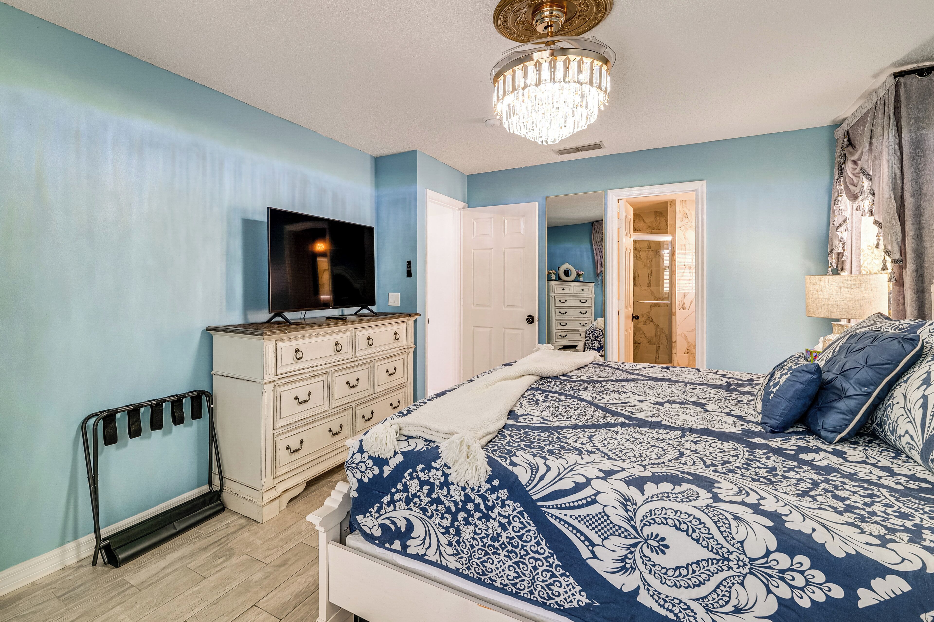 Ein Schlafzimmer mit Bett, Schminktisch, Fernseher und einer Chandel.