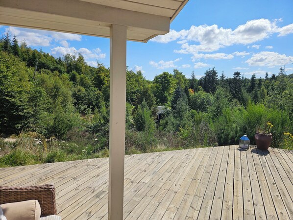 A wooden deck with a view of dense forest and a clear sky. - Fantastic house with a beautiful view (Ebeltoft)