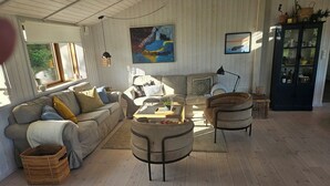 Una sala de estar acogedora con un sofá, sillones, una mesa de centro y un aparador.