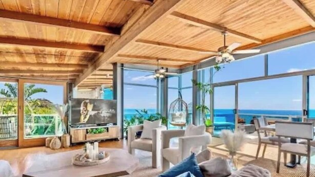 Ein modernes Wohnzimmer mit Holzboden, großen Fenstern und Meerblick.