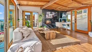 Ein geräumiges Wohnzimmer mit Holzboden, Kamin, Sofa und Fernseher.