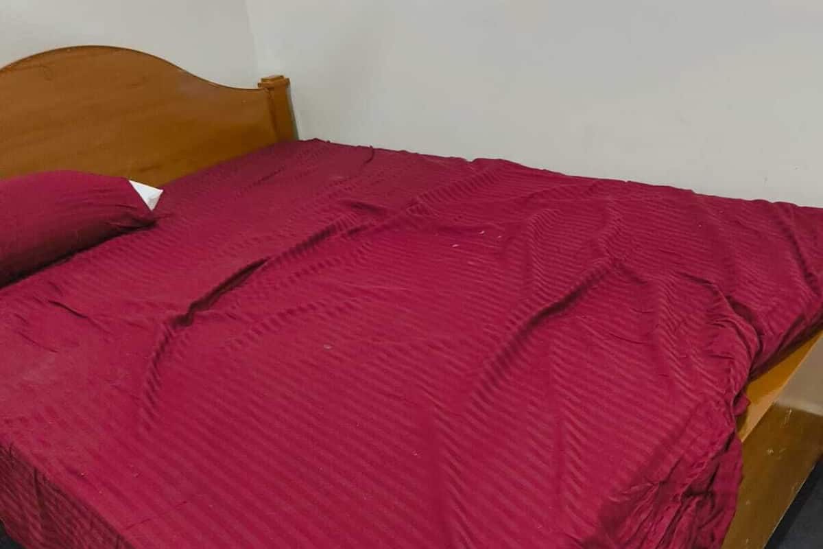 Una cama con cabecera de madera y colcha roja.