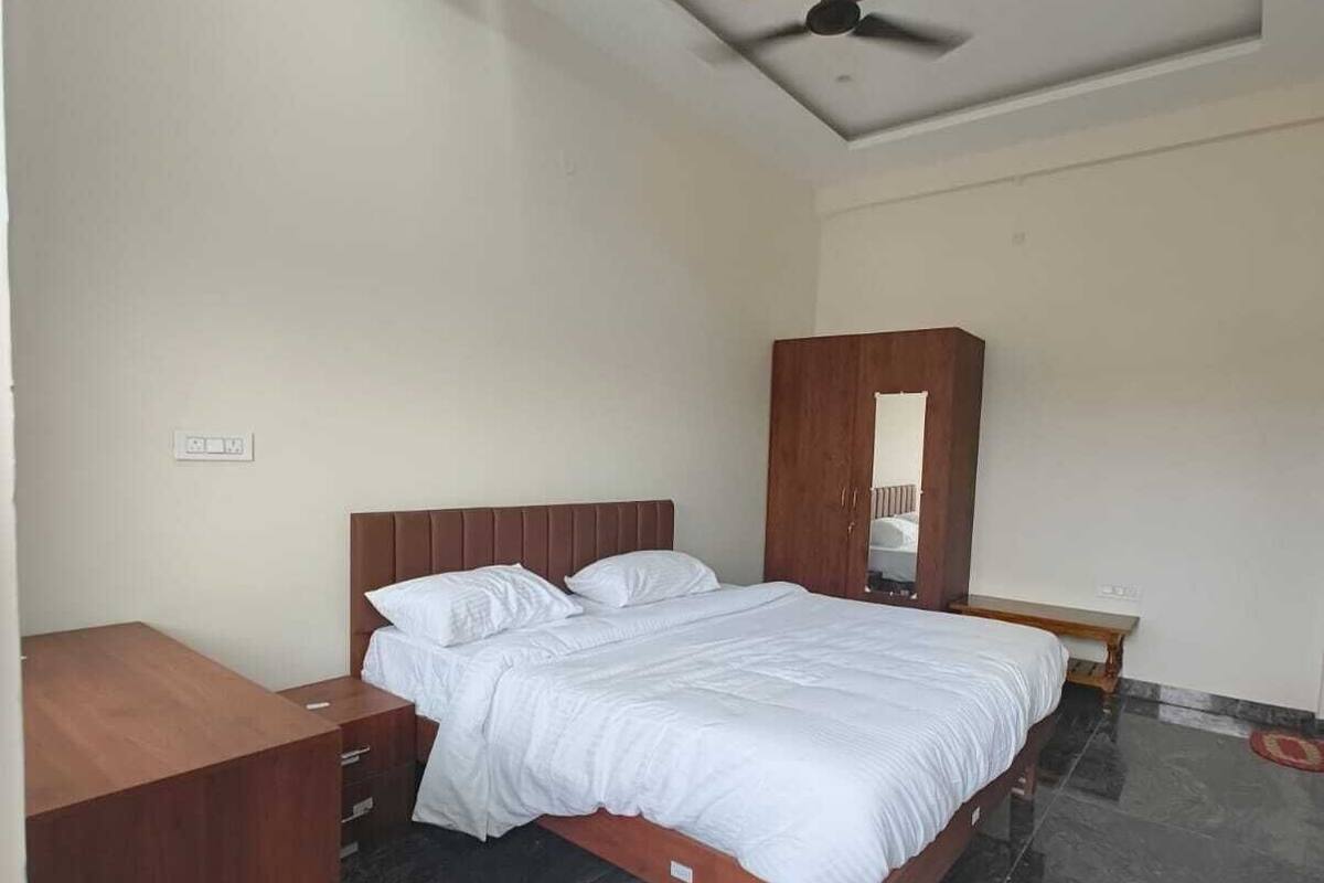 Un dormitorio con cama, mesitas de noche de madera, un armario, ventilador de techo y suelo de mármol.