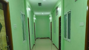 A hallway with green walls, wooden doors, and tiled flooring. - Annamalaiyar Mahal & Residency (Chengam)