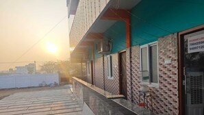 A building with a tiled exterior, a water dispenser, and a sign with contact numbers. - Annamalaiyar Mahal & Residency (Chengam)