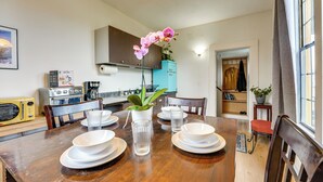 A dining area with a wooden table set for four, surrounded by chairs. A vase with a pink orchid is placed in the center. - Gateway to Adventure! Dtwn Toledo Home Near Hiking (Toledo)
