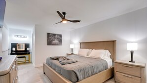 A modern bedroom with a bed, bedside tables, a ceiling fan, and a desk with a mirror. - Old Town Oasis! Modern Unit w/ Resort-Style Pool (Scottsdale)