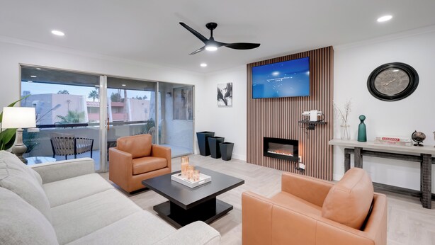 A modern living room with a sofa, armchairs, a coffee table, a TV, a fireplace, and a balcony with a view. - Old Town Oasis! Modern Unit w/ Resort-Style Pool (Scottsdale)