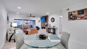 A modern living room with a glass-top dining table, comfortable seating, a flat-screen TV, and a fireplace. - Old Town Oasis! Modern Unit w/ Resort-Style Pool (Scottsdale)