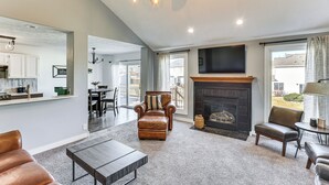 Un salón amplio con chimenea, muebles de cuero y un televisor grande.