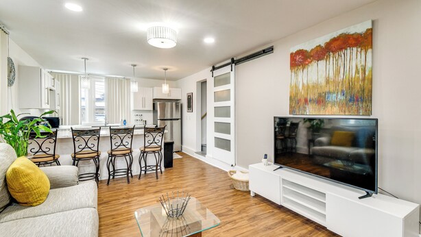A modern living room with a TV, sofa, and dining area. - Explore Rochester! Charming Home 1 Mi to Downtown (Rochester)