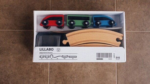 A box containing three toy cars and wooden train tracks.
