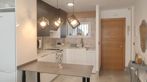 Eine moderne Küche mit einer Glastischplatte, Pendelleuchten und einer Holztür.