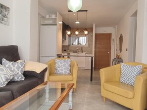 A modern living room with a glass coffee table, two sofas, and a kitchen in the background. - Nerja Sun Apartments Bahia 7 (Nerja)