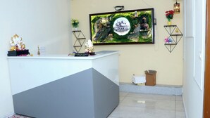 A reception desk with a check-out sign, a framed cityscape poster, and decorative items including a Buddha statue and plants. - The City View- Hotel And Restaurant (Bhiwani)