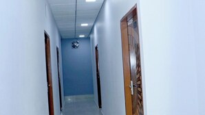A corridor with white walls, a blue door, and a ceiling with recessed lighting. - The City View- Hotel And Restaurant (Bhiwani)