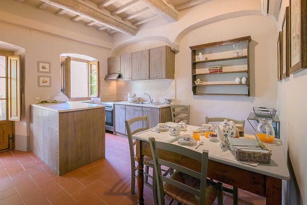 A kitchen with wooden cabinets, a dining table set with plates, cups, and a basket.