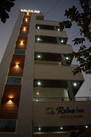 Un bâtiment sur lequel on peut lire l’inscription « Relax Inn Suites & Rooms » et qui possède de nombreuses fenêtres illuminées.