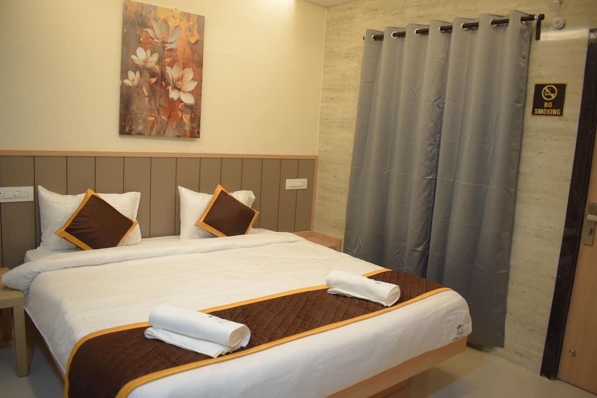A hotel room with a large bed, a headboard, a painting on the wall, and a shower curtain with a no smoking sign.