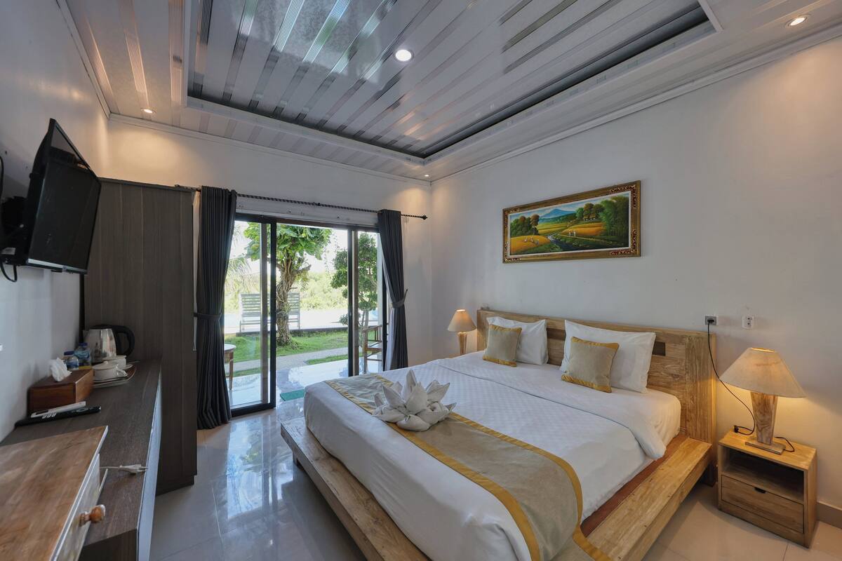 Une chambre d’hôtel avec un grand lit, un bureau, une télévision et un tableau au mur.