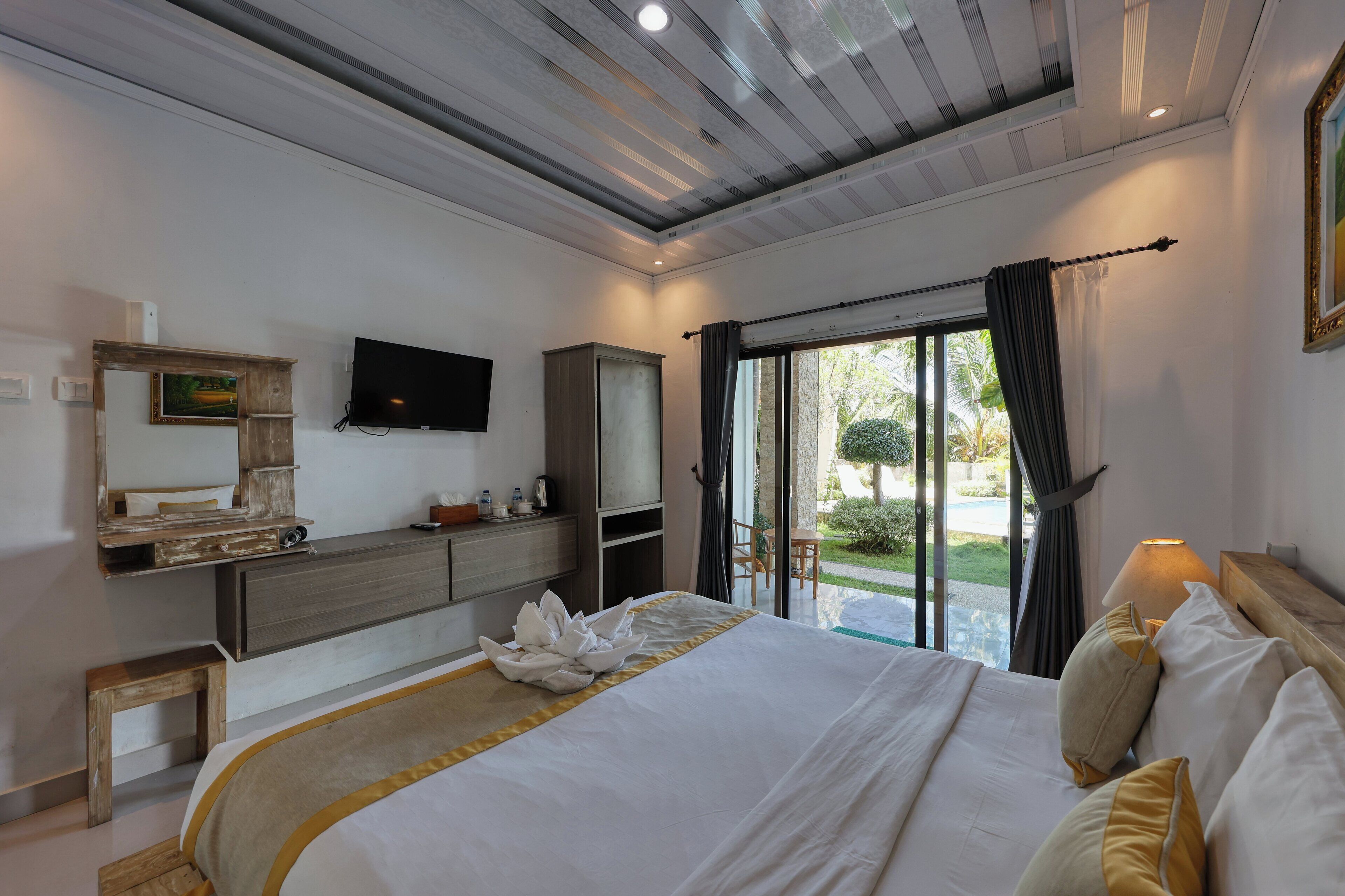 Habitación de hotel moderna con una cama grande, un televisor de pantalla plana, un armario de madera y vistas al exterior.