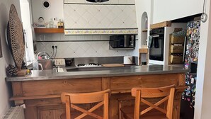 Eine Küche mit einer Holzinsel, zwei Barhocker, einer Mikrowelle und einem Kühlschrank.