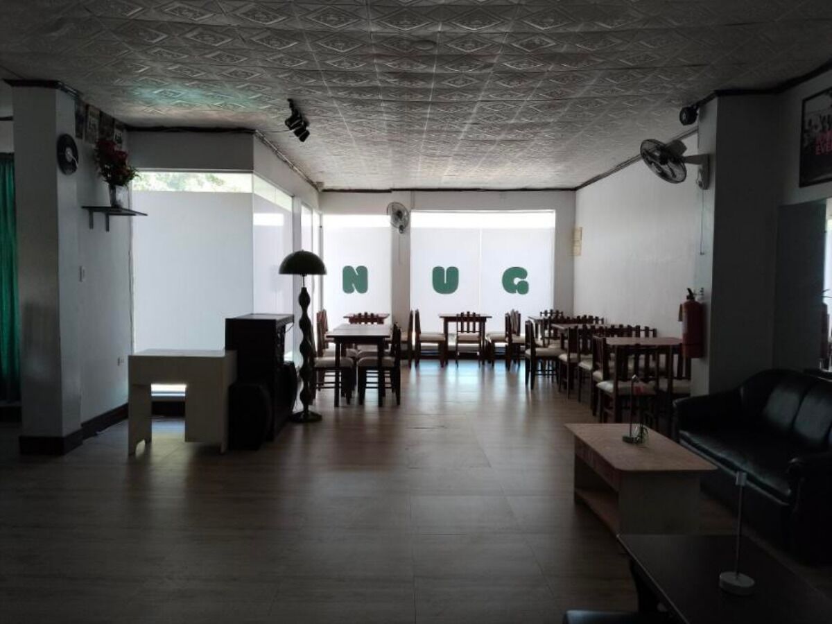 A spacious room with a large window, a chess table, and several chairs arranged for dining.