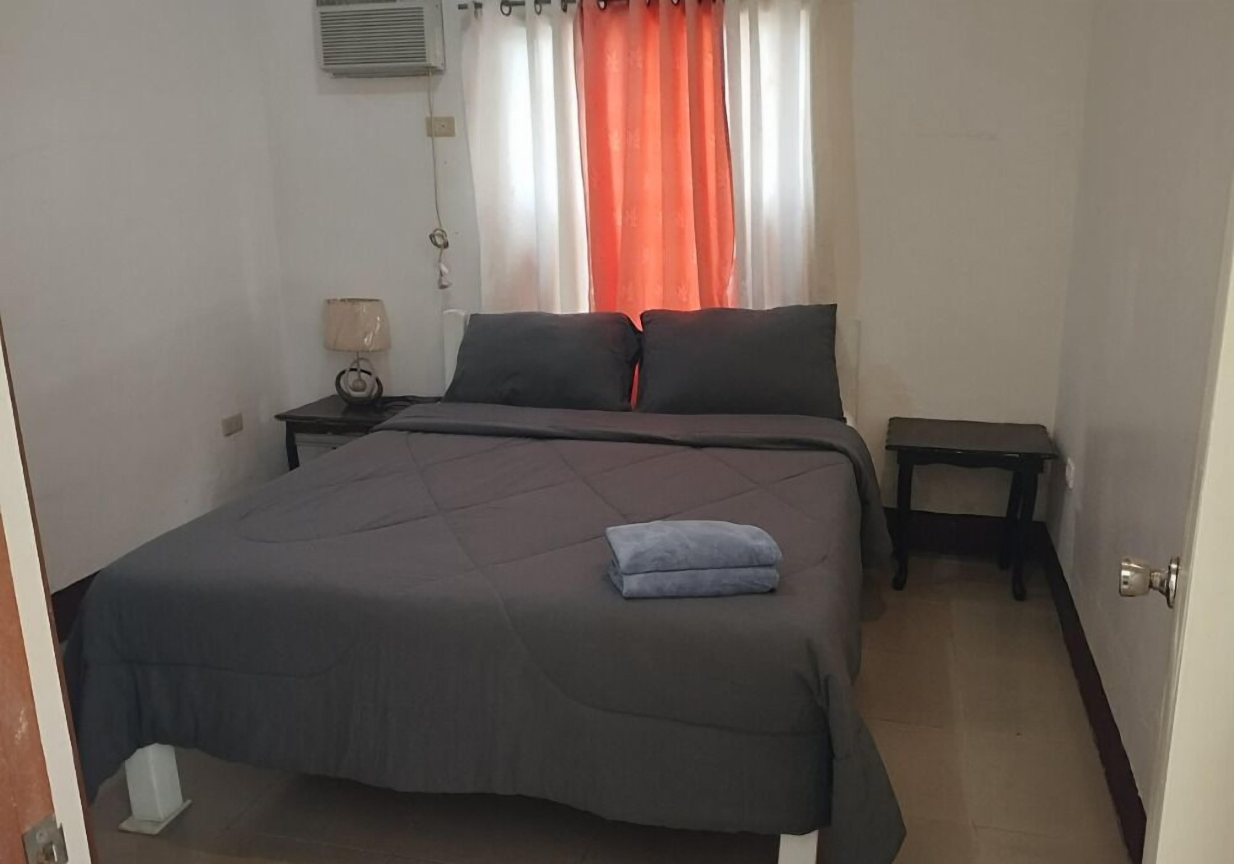 A bedroom with a large bed, a bedside table with a lamp, and a small table beside the bed.