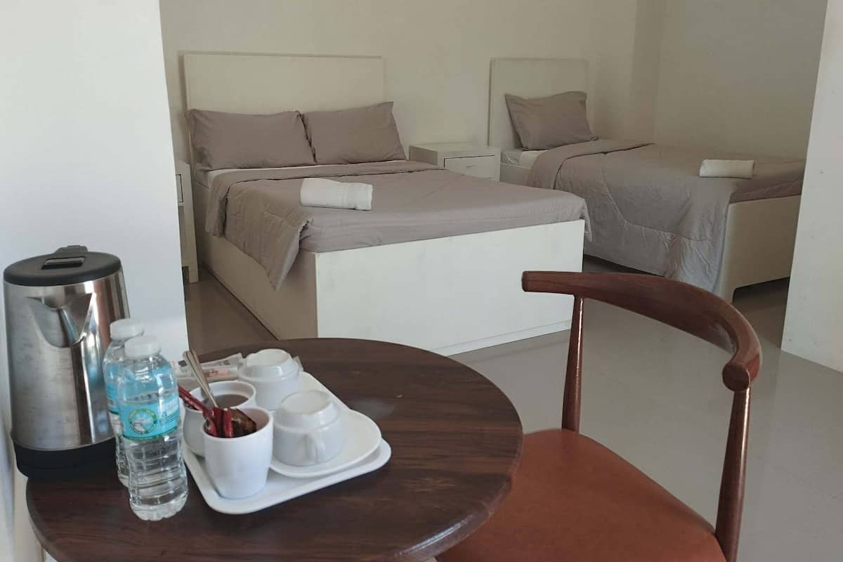 Une chambre d'hôtel comprenant un lit, une chaise, une table avec un plateau de produits pour le petit-déjeuner et un distributeur d'eau.