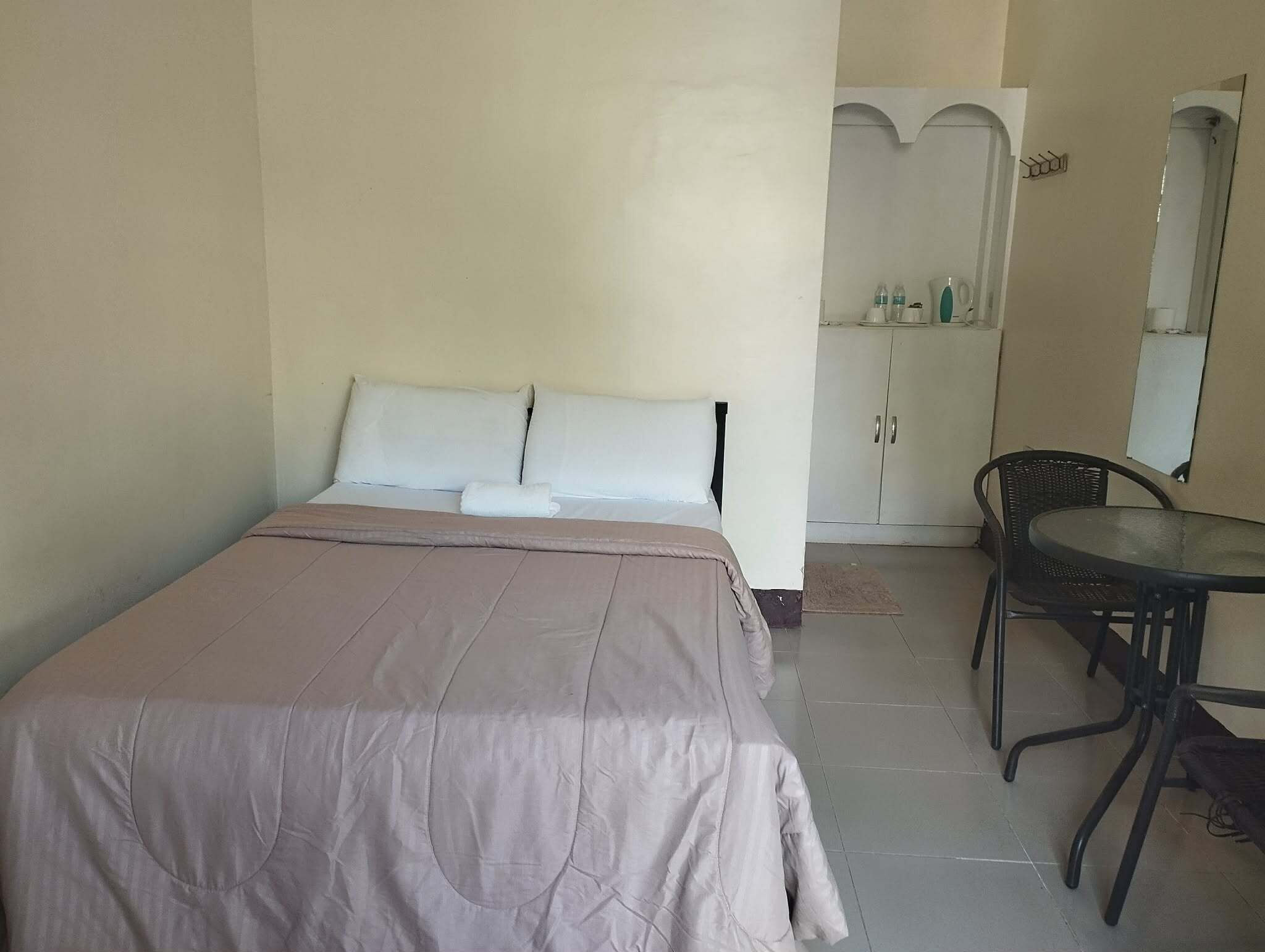 A simple room with a bed, a small table, and a chair.